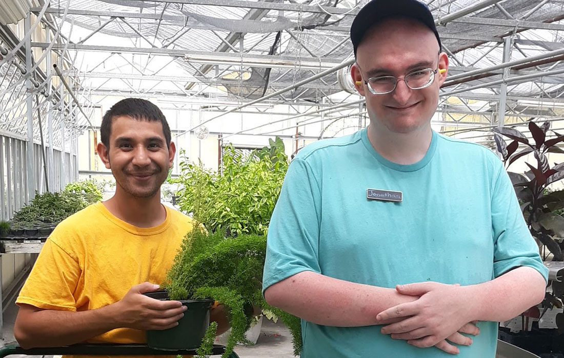 Two volunteers smiling and helping with plants.